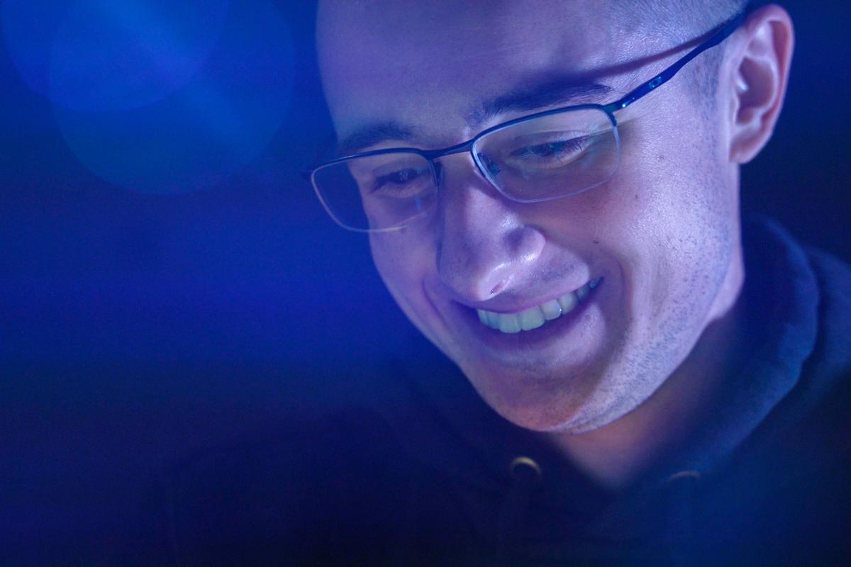 A male student smiles while looking at a presentation