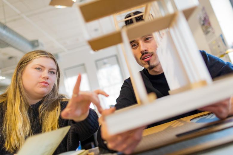A female and male student examine an architectural model.